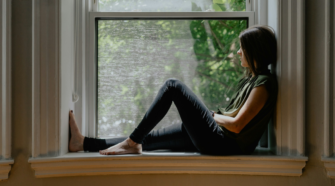 Imposter Syndrom - a woman self-reflecting, staring out the window.